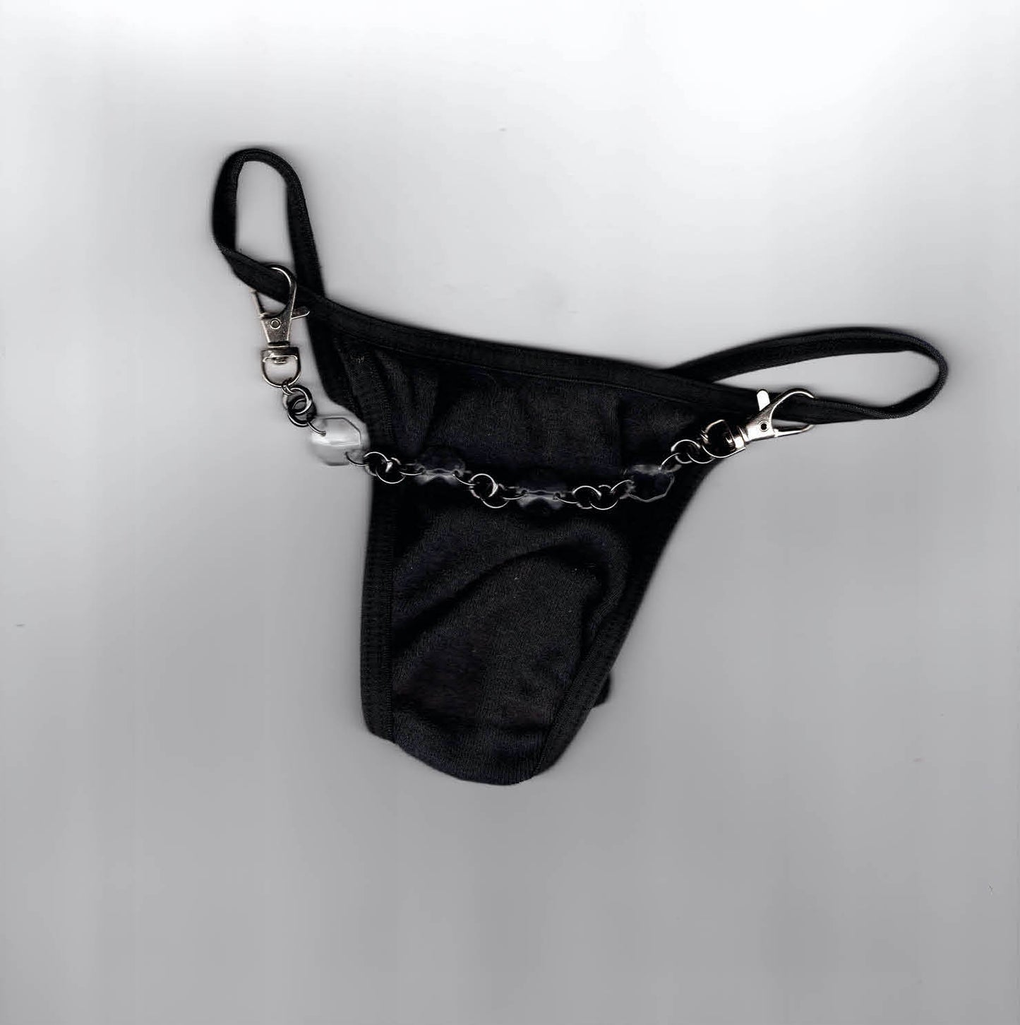 Accessoire de lingerie artisanal Ines Pineau, string noir accessoirisé d'une chaîne upcyclée avec perle et mousquetons, création parisienne.