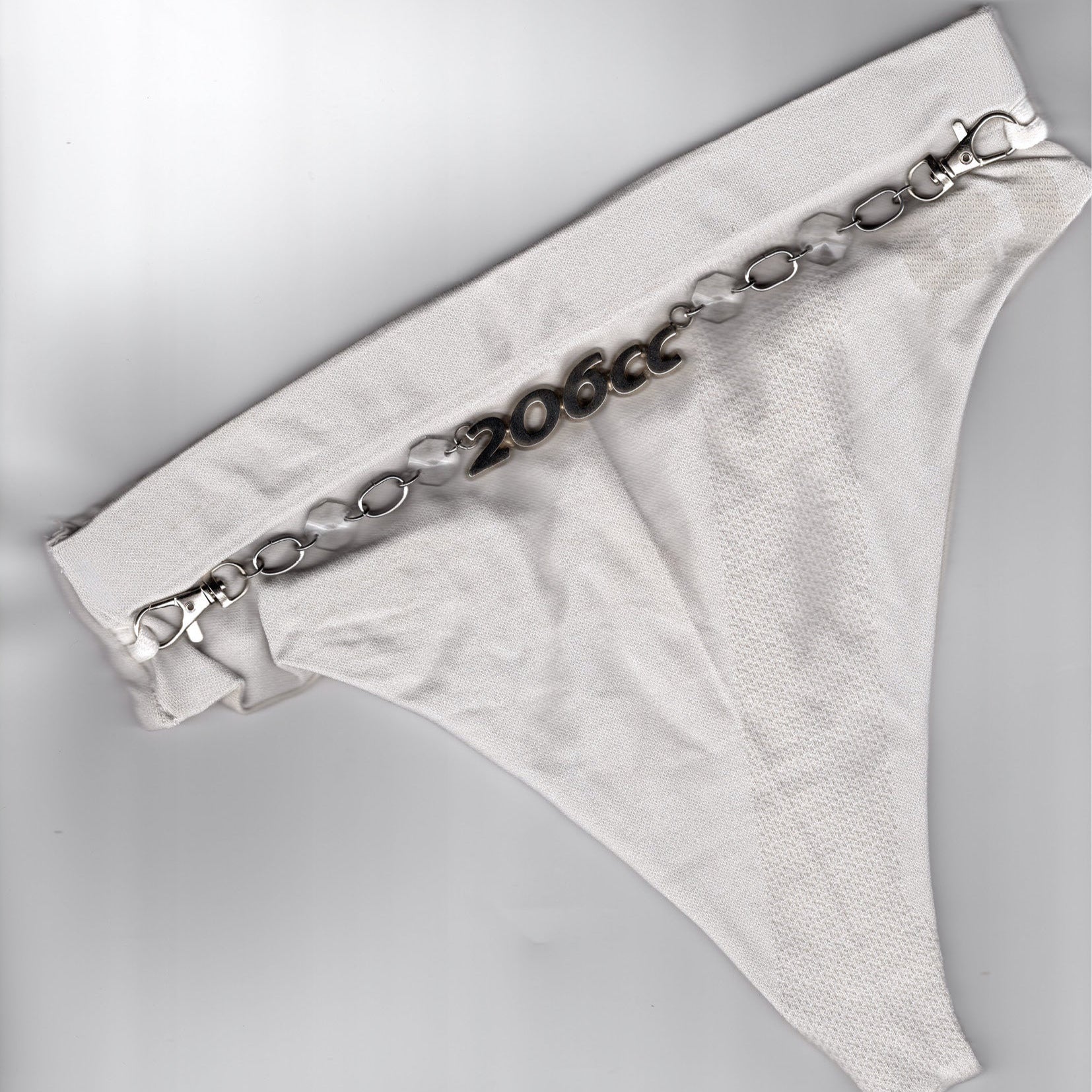 Bijou de corps et accessoire de lingerie upcyclé Ines Pineau, string noir orné d'une chaîne métallique avec médaillon 206 CC, fait main à Paris.